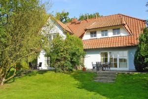 a white house with a yard with chairs and tables at Ferienwohnungen Blaues Haus, Putbus in Putbus