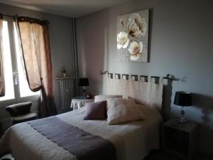 ein Schlafzimmer mit einem Bett und einem Blumenbild an der Wand in der Unterkunft L'Orée du Parc à Belfort in Belfort