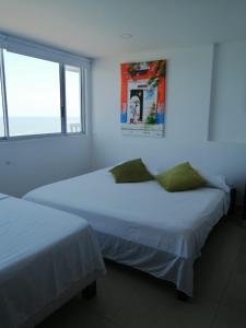 2 Betten in einem weißen Zimmer mit Fenster in der Unterkunft Apartamentos en Palmetto in Cartagena de Indias