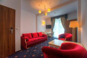 a hotel room with a red couch and chairs at Hotel Łańcut in Łańcut