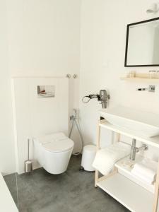 a white bathroom with a toilet and a sink at Casa da Umbria in Odemira