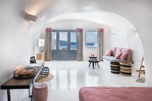 uma sala de estar com um sofá e uma mesa em Maregio Suites em Oia