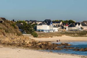 - un groupe de maisons sur une plage au bord de l'océan dans l'établissement Hotel Restaurant De La Plage, à Audierne