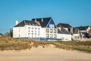 een groot wit gebouw aan het strand naast een strand bij Hotel Restaurant De La Plage in Audierne