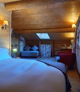 een slaapkamer met een bed en een bank in een kamer bij La Ferme du Chozal, Chalet de tradition in Hauteluce