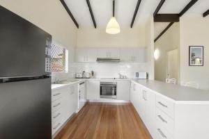 a kitchen with white cabinets and a wooden floor at William St 1 70 Moffat Beach in Caloundra