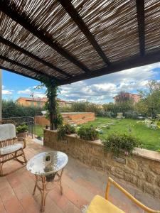 eine Terrasse mit einer hölzernen Pergola und einem Tisch in der Unterkunft Antica Casa del Glicine in Poggibonsi