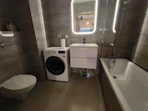 a bathroom with a toilet sink and a washing machine at Apartamenty Wola in Warsaw