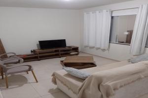 a white room with a tv and a bed and a chair at Dream House Hospedagens in Itacimirim