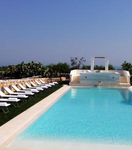 a swimming pool with chaise lounge chairs and a swimming pool at Masseria Corte degli Asini in Montalbano