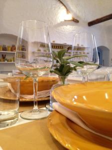 a table with two wine glasses and plates on it at Masseria Corte degli Asini in Montalbano