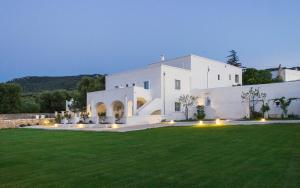 a large white house with a lawn at night at Masseria Corte degli Asini in Montalbano