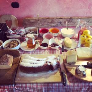 una tavola ricoperta di formaggio, pane e altri prodotti alimentari di La Ferme du Grand Paradis a Cogne