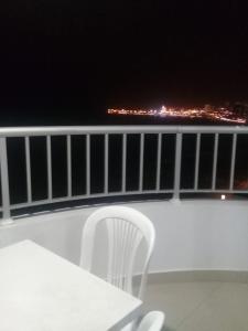 ein weißer Stuhl, der nachts auf einem Balkon sitzt in der Unterkunft Apartamentos en Palmetto in Cartagena de Indias