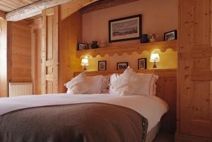 una camera da letto con un grande letto con cuscini bianchi di La Ferme du Chozal, Chalet de tradition a Hauteluce