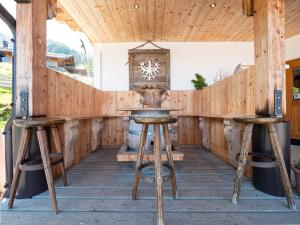 a bar with stools and a clock on the wall at Balbach Alm Apartment in Oetz