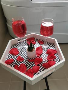 - une table avec deux verres à vin et des roses rouges dans l'établissement Iași Jacuzzi Apartment H, à Iaşi