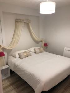 1 dormitorio con 1 cama blanca grande y 2 almohadas en Hôtel Beau Rivage, en Royan