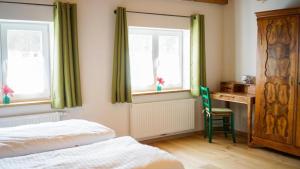 a bedroom with a bed and a desk and two windows at Ferienwohnung Trendelmühle Lautrach in Lautrach