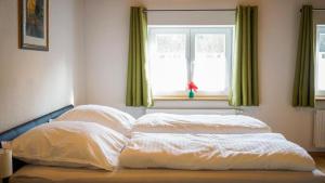 a bed with two pillows in front of a window at Ferienwohnung Trendelmühle Lautrach in Lautrach