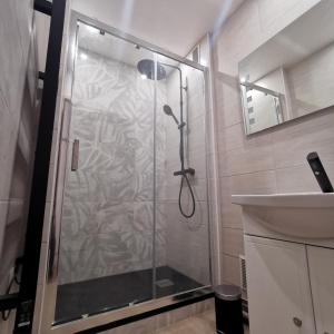 a shower with a glass door next to a sink at Chambre Evasion Tout confort Saint Marceau in Orléans