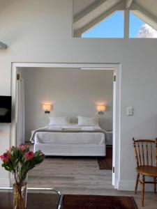 - une chambre avec un lit blanc et une chaise dans l'établissement Camps Bay Loft with Stunning Mountain and Ocean Views, au Cap