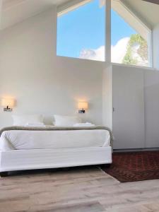 a white bedroom with a large bed and a window at Camps Bay Loft with Stunning Mountain and Ocean Views in Cape Town
