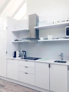 una cocina blanca con armarios y electrodomésticos blancos en Camps Bay Loft with Stunning Mountain and Ocean Views, en Ciudad del Cabo