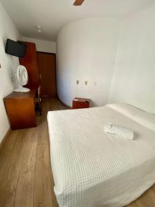 1 dormitorio con cama blanca y suelo de madera en Porto Rei Residence Hotel, en Río Grande