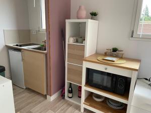 una pequeña cocina con mesa y microondas en Joli petit STUDIO 2, en Menneval