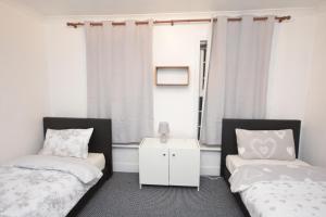 1 dormitorio con 2 camas y ventana en Lovely 3 Bedroom House near Barking Station en Barking