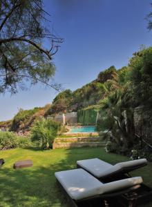 un prato con sedie a sdraio e una piscina di Maridea - La Caletta - Luxury Villa a Ponza