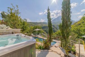 a hot tub in a garden with mountains in the background at MarcheAmore - La Roccaccia relax, art & nature in Montefortino