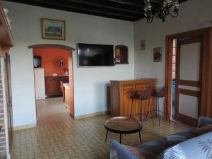 a living room with a couch and a tv on the wall at LA FERMETTE DE L'YERES in Aubermesnil