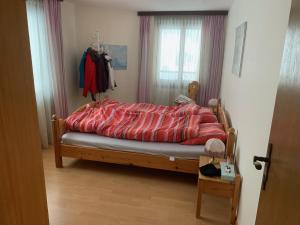 ein Bett mit einer roten Bettdecke in einem Schlafzimmer in der Unterkunft Casa Surselva Whg Bilger in Savognin