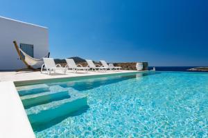 a pool with lounge chairs and the ocean in the background at VILLA ERIS in Agios Georgios