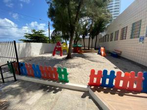 un parque infantil con una valla de juguetes y un árbol en Flat beira mar, Olinda 4 Rodas 315 en Olinda