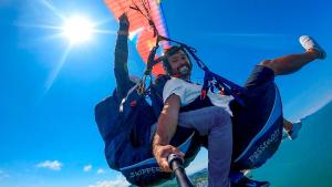 two men are on a parachute in the sky at 3x6 Lofts in Balneário Camboriú