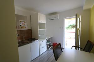 a kitchen with white cabinets and a table with chairs at Antodo Alen in Novalja