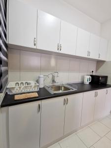 a kitchen with white cabinets and a sink at 3 Astetica Residences The Mines 4BR WiFi Netflix Lake View in Seri Kembangan