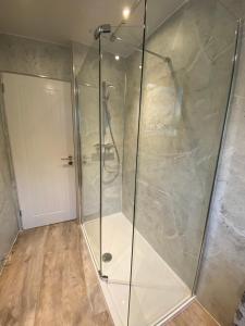 a shower with a glass door in a bathroom at Tweed Green Holiday let in Peebles