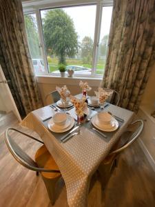 a table with plates and dishes on it in front of a window at Tweed Green Holiday let in Peebles