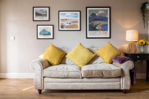 a living room with a gray couch with yellow pillows at Windy Ridge Terrace with beautiful sea views, North Wales Coast in Old Colwyn