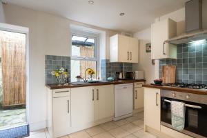 a kitchen with white cabinets and a window at Windy Ridge Terrace with beautiful sea views, North Wales Coast in Old Colwyn