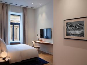 um quarto de hotel com uma cama, uma secretária e uma televisão em xenodocheio Milos em Atenas