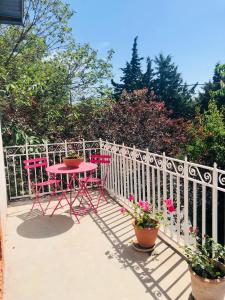 een rode tafel en stoelen op een balkon met bloemen bij Winemaker’s House with pool near the sea in Saint-Geniès-de-Fontedit