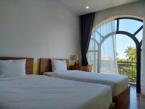 two beds in a hotel room with a large window at Golden Sunshine Villa in Hiếu Nhơn