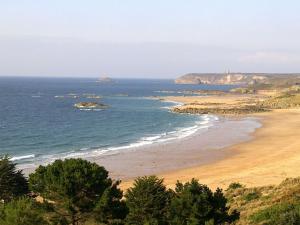 a view of a beach with a lighthouse in the distance at Apartment in Erquy near Emerald Coast Beaches in Erquy