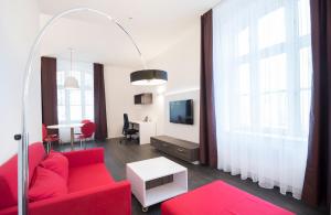 ein Wohnzimmer mit einem roten Sofa und einem Tisch in der Unterkunft Boardinghaus Weinberg Campus in Halle an der Saale