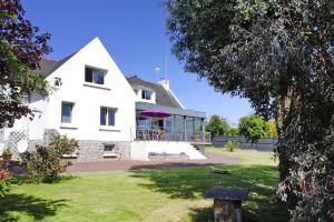 een groot wit huis met een veranda op een gazon bij Cottage, Ploubazlanec in Ploubazlanec